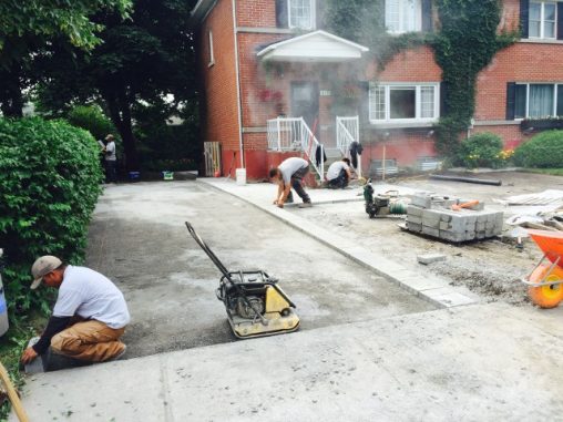 Ouvriers effectuant la pose de dallage à l'avant d'une maison