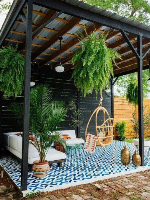 Salon extérieur sous une pergola avec plantes suspendues