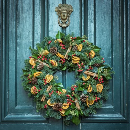 Couronne de Noël avec agrumes séchés sur une porte bleue