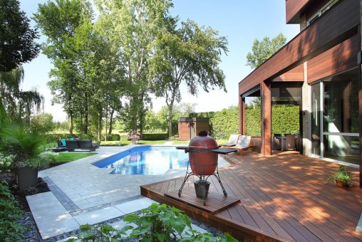 Terrasse arrière en bois avec piscine, pavé et barbecue