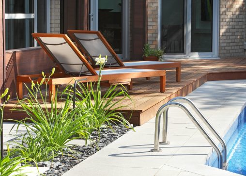 Chaises longues sur une terrasse de bois attenante à une piscine creusée