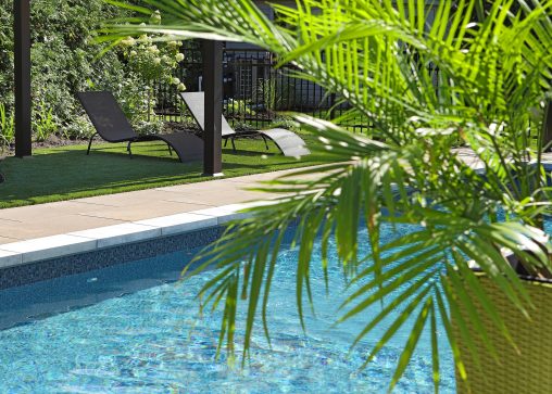 Aménagement paysager avec piscine, chaises longues et plante verte tropicale