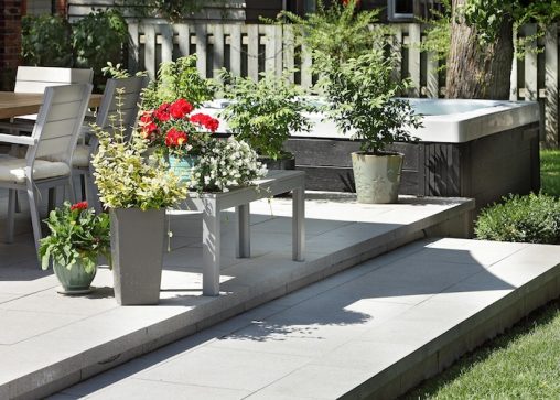 Terrasse en pavé avec fleurs et plantes en pots, attenante à un spa